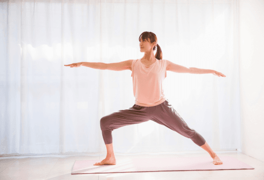 A woman practices Warrior II Preparation (Virabhadrasana II)