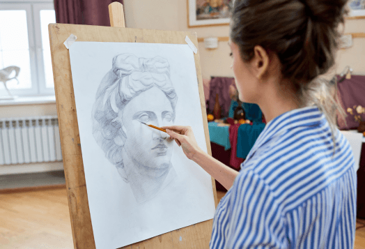 A woman draws a portrait of a classical sculpture on an easel