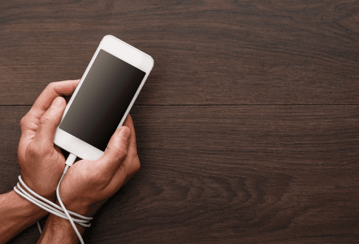 Hands are tied with a phone charging cable, suggesting phone addiction