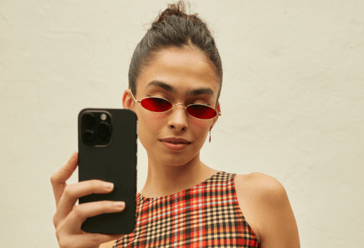 Woman with red glasses holds up a smartphone to take photo