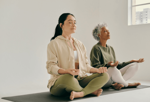 Two women meditating on yoga mats in a studio