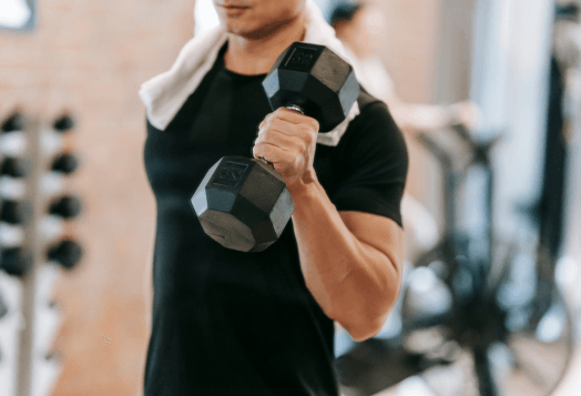 Man with towel on shoulder lifting a dumbbell
