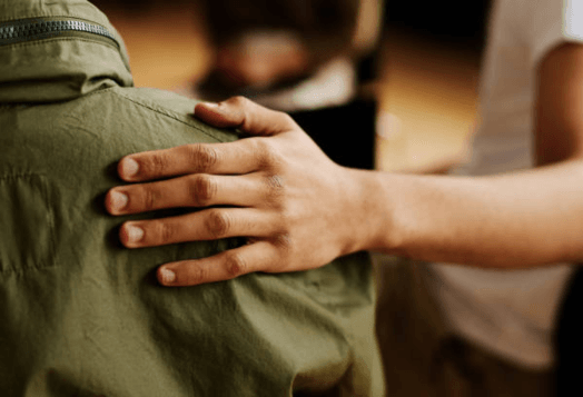A hand gently resting on another person's shoulder
