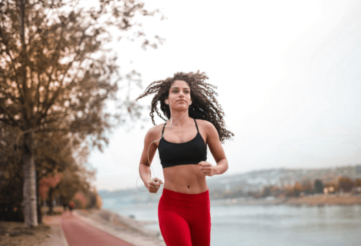 Woman with curly hair running outdoors by a river