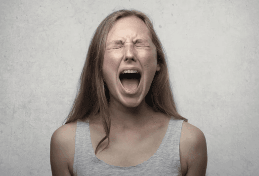 Woman with closed eyes, screaming in distress