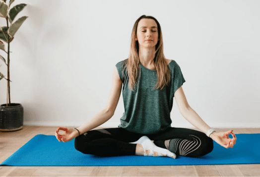 Woman meditating in Sukhasana on a blue yoga mat