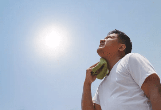 A man with a towel wiping his neck from sweat