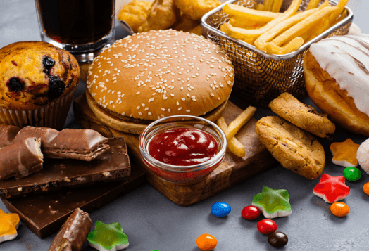 A variety of unhealthy foods, including a burger, fries, and candy