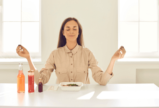 A woman with closed eyes, meditating with a takeout meal in front of her