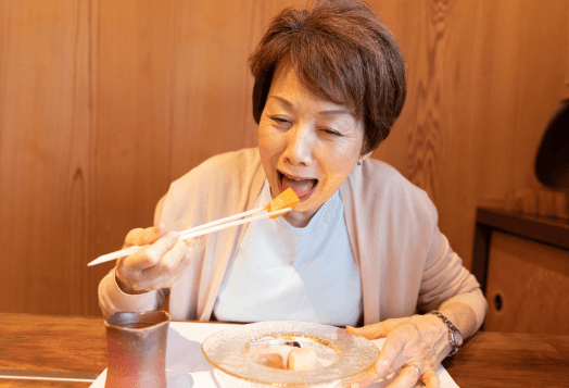 An older woman enjoying her meal with chopsticks