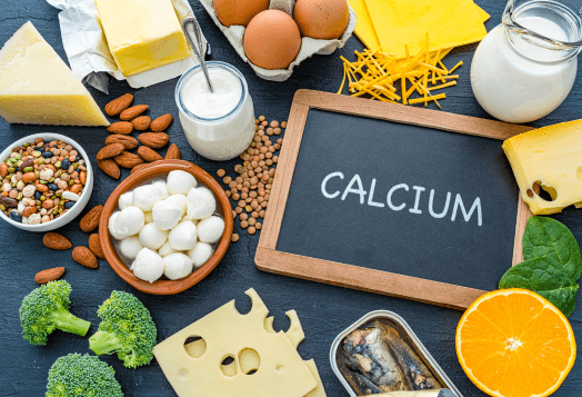 A flat lay of calcium-rich foods on a dark surface, with a chalkboard sign that says 'CALCIUM'