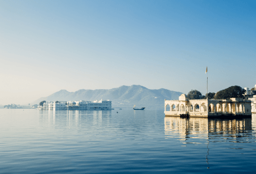 White palace on calm lake with mountains behind