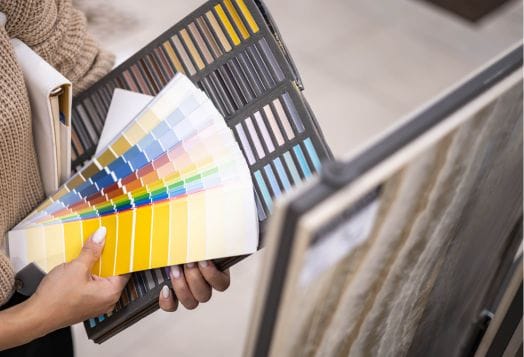 Hands holding color swatches and tile samples