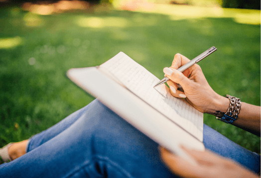 Person writing in a notebook outdoors