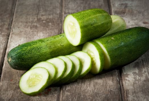 Sliced and whole cucumbers on wood