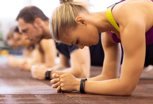 Four people doing forearm planks in a row