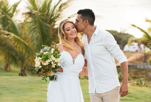 Groom kissing bride at tropical wedding