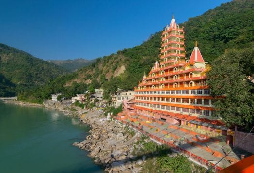 Colorful temple by river in Rishikesh hills
