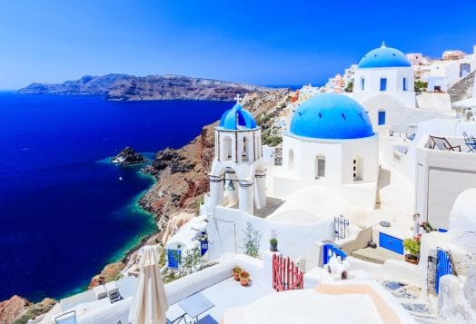Whitewashed buildings with blue domes by sea