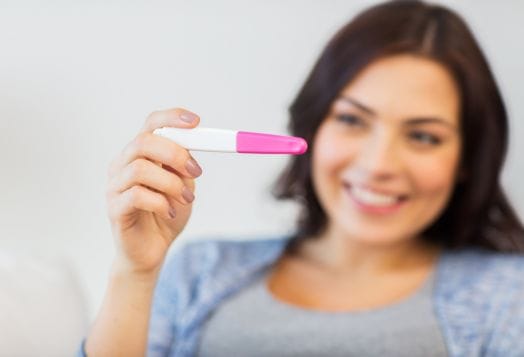 Woman holding pregnancy test while trying to conceive