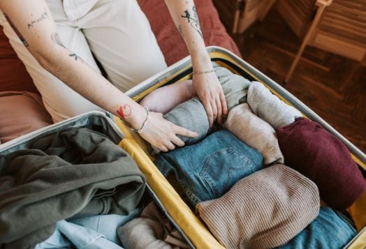 Person packing clothes into open suitcase