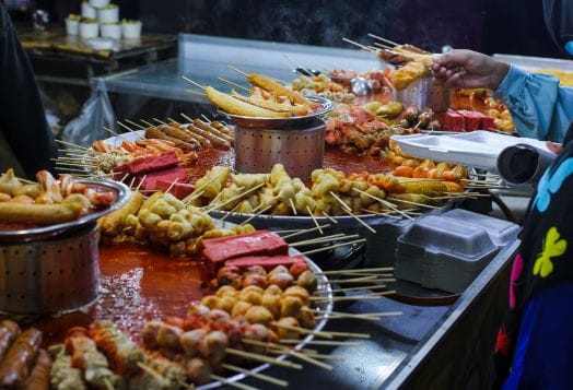 Variety of skewered food on street vendor table