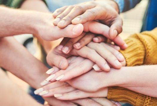 Group of diverse hands stacked together in unity and teamwork
