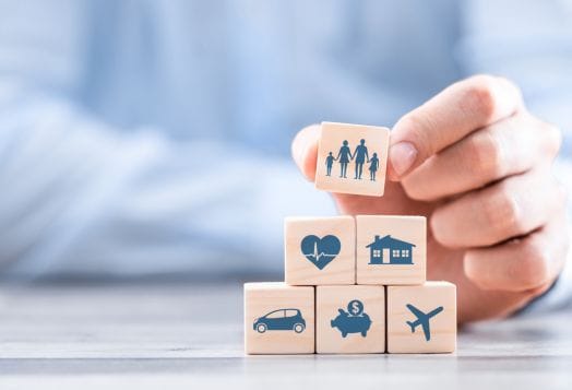 Hand stacking wooden blocks with insurance icons