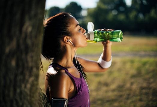 Woman drinking water after exercising outdoors
