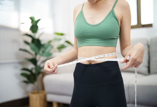 Woman measuring her waist with a tape measure