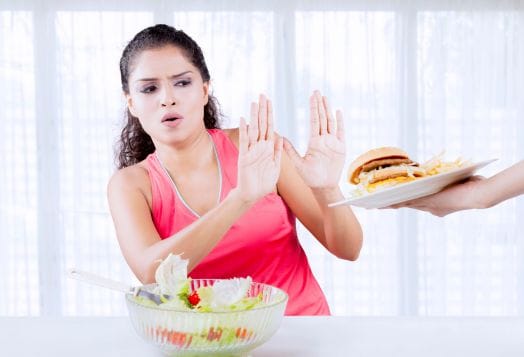 Woman refusing burger, eating salad