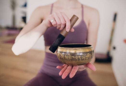 Woman using Tibetan bowl for sound healing meditation