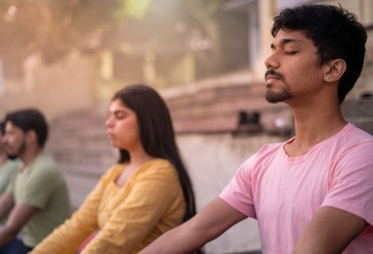Group practicing meditation for stress relief outdoors