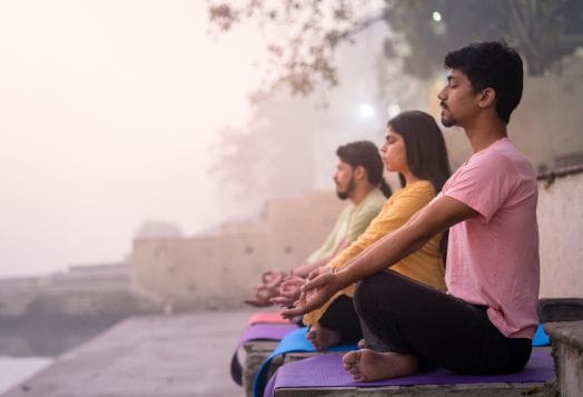 Group practicing pranayama breathing outdoors at sunrise