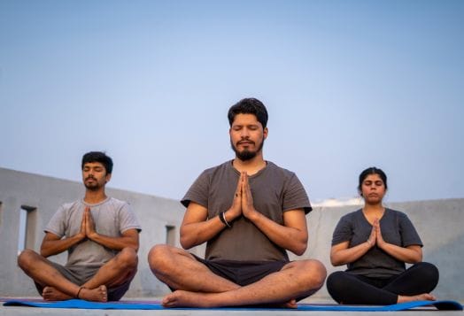 Group practicing pranayama breathing outdoors at sunset