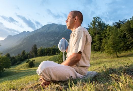 Man practicing mantra yoga outdoors with prayer beads