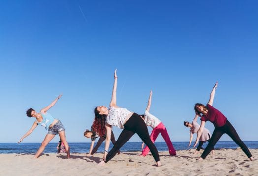Group practicing modern yoga on the beach for fitness
