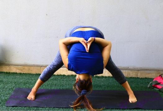 Woman doing Standing Forward Fold with twist exercise