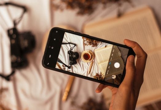 Hand holding a phone taking a flat lay photo