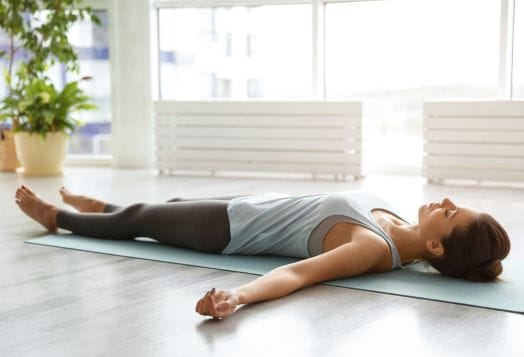 Woman in savasana pose enjoying relaxation and wellness benefits