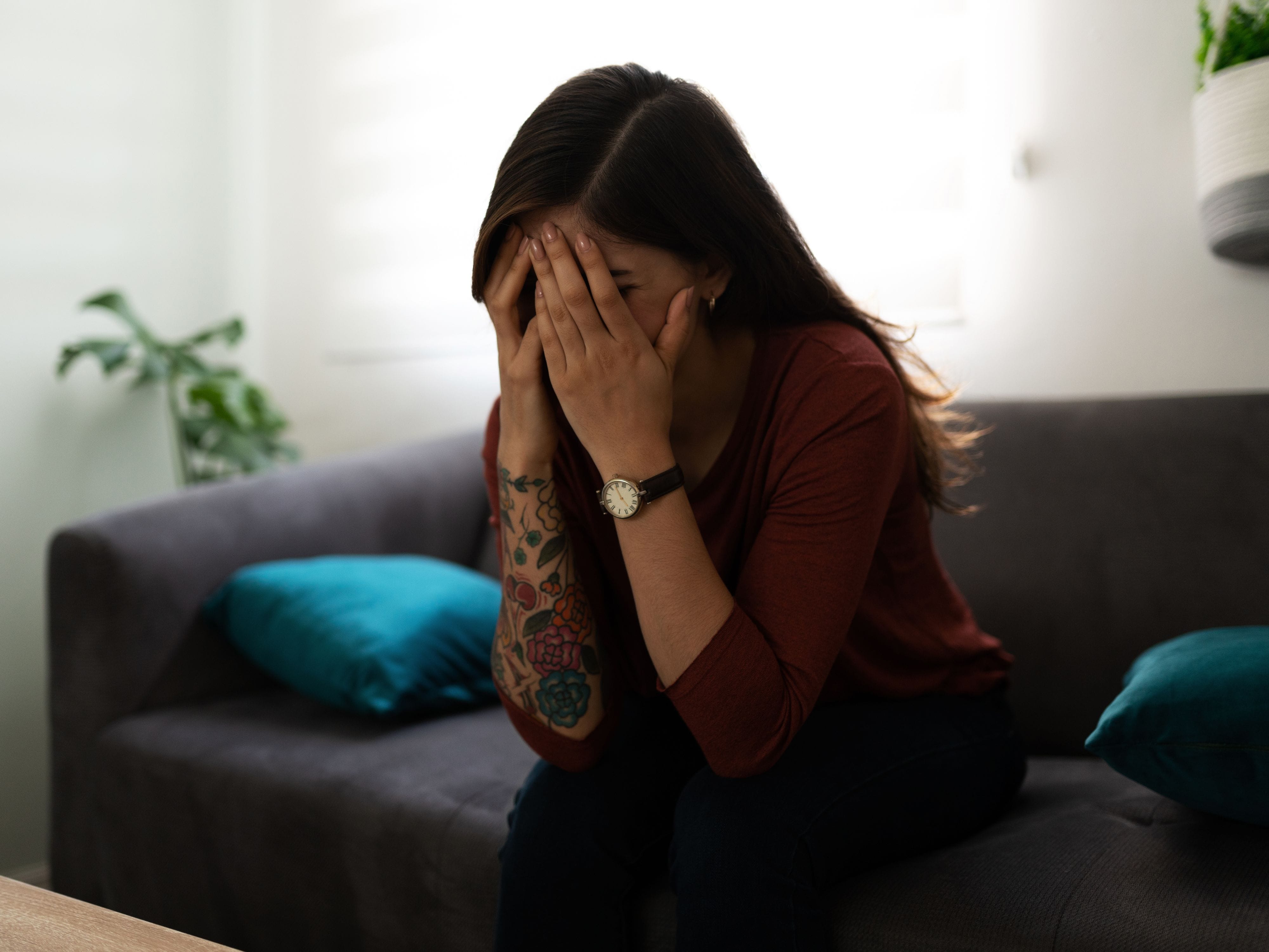 Sad woman with head in hands on couch