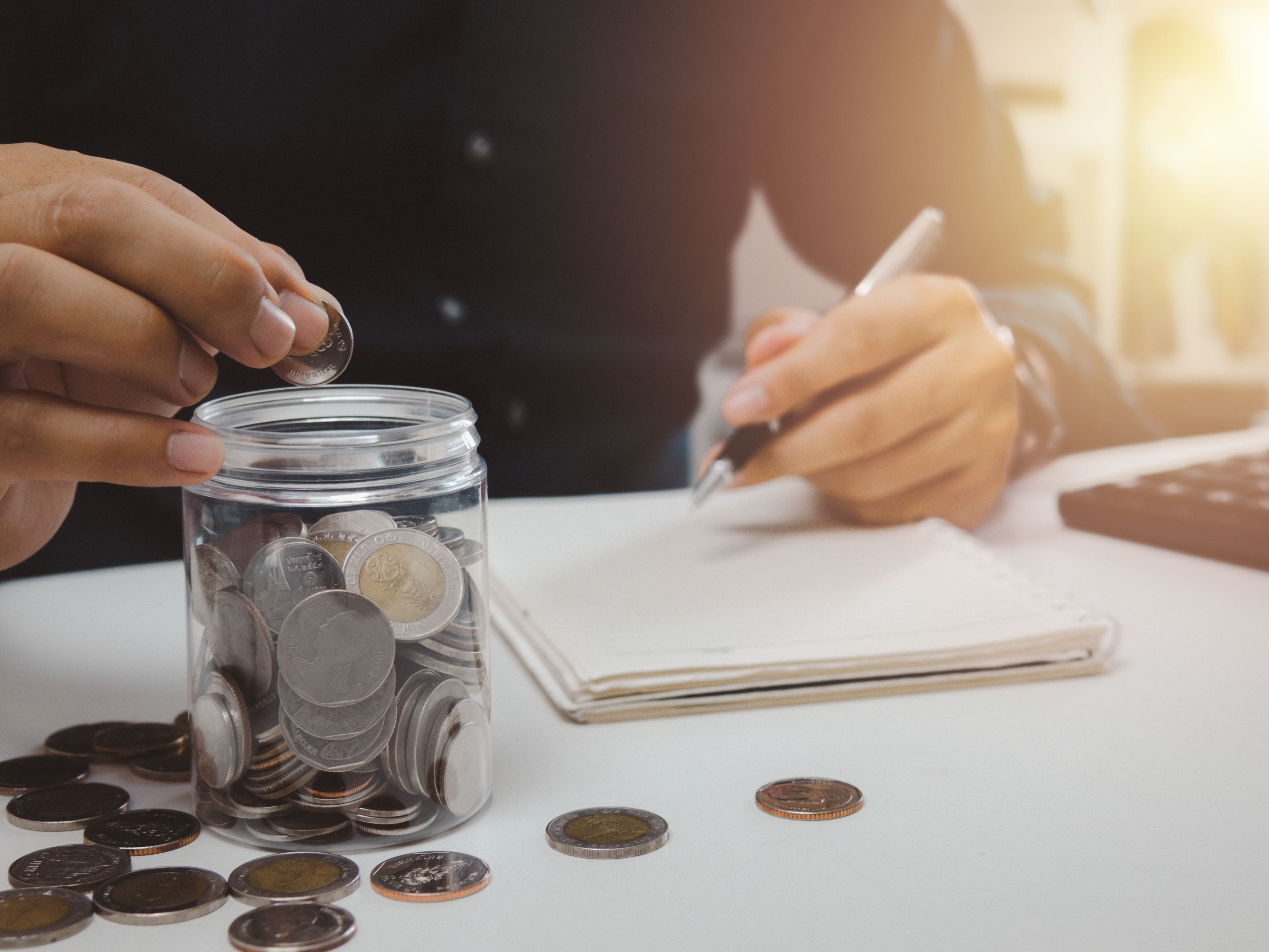 Hands putting coins in a jar