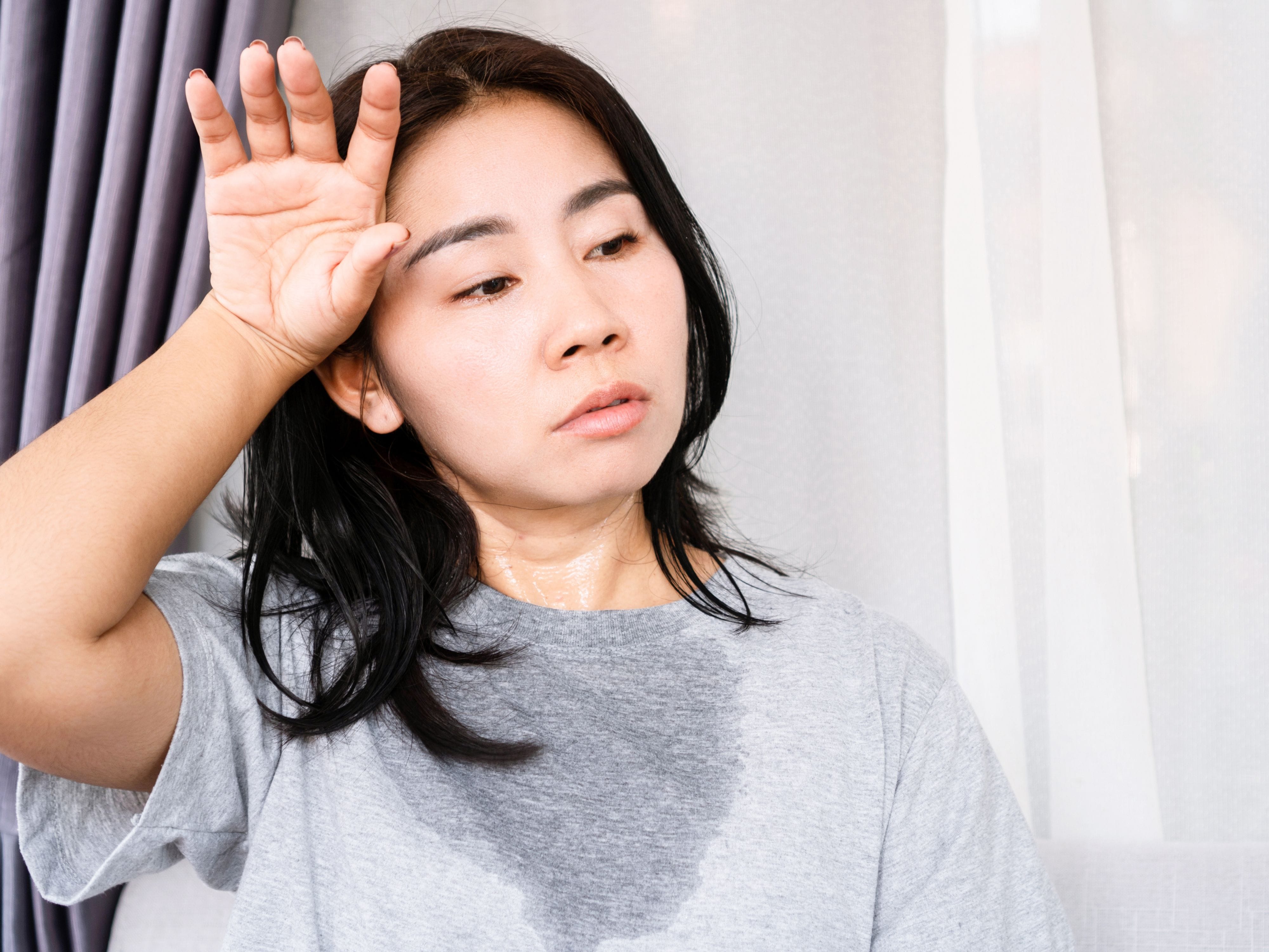 A woman sweating and wiping it off with her hand