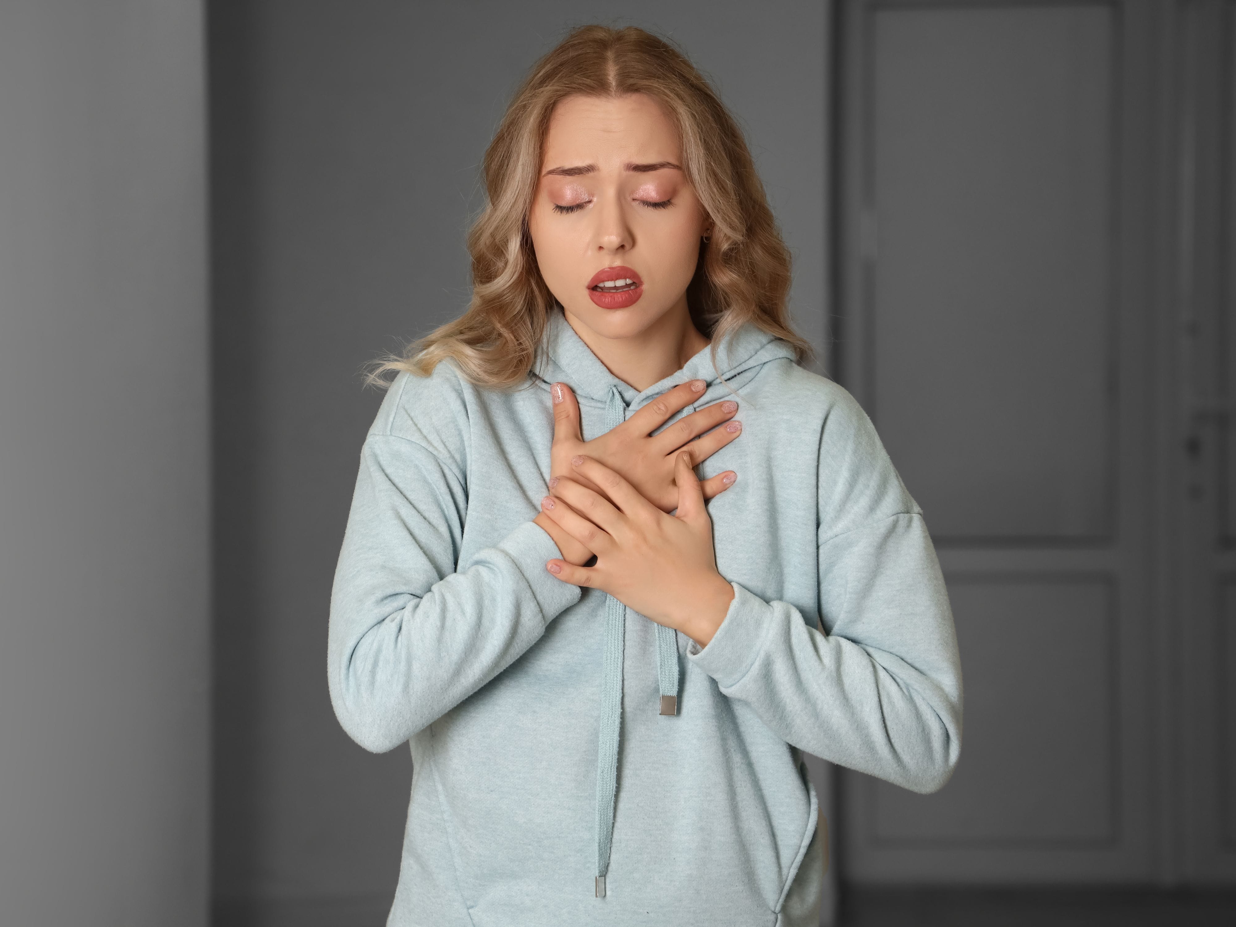 A woman panicking, holding her chest as she gasps