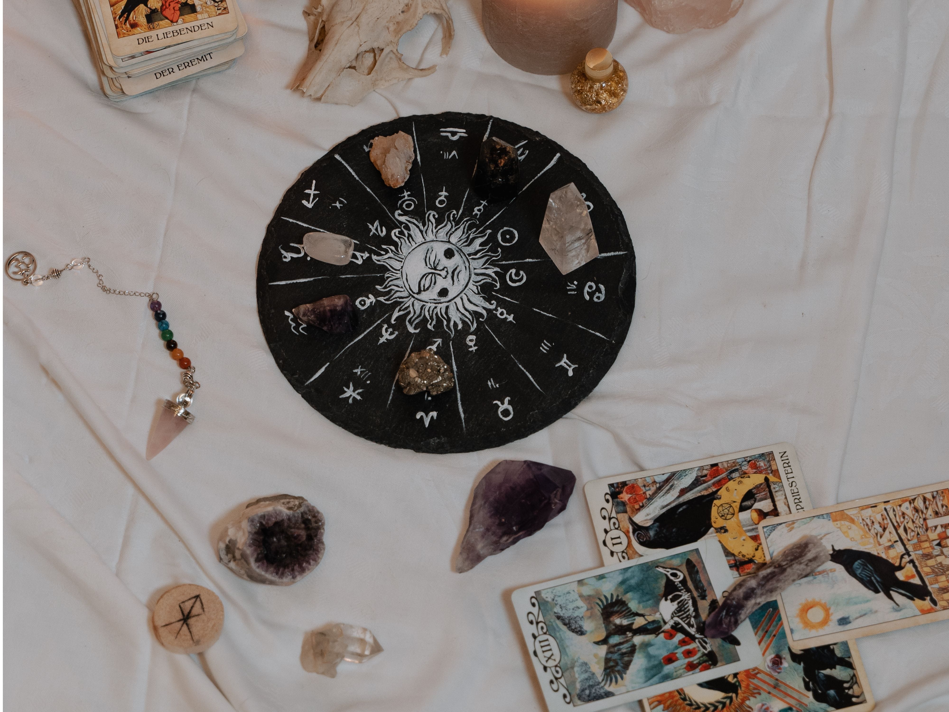 A Nakshatra circular tile surrounded by tarot cards and crystals placed on individual sun signs