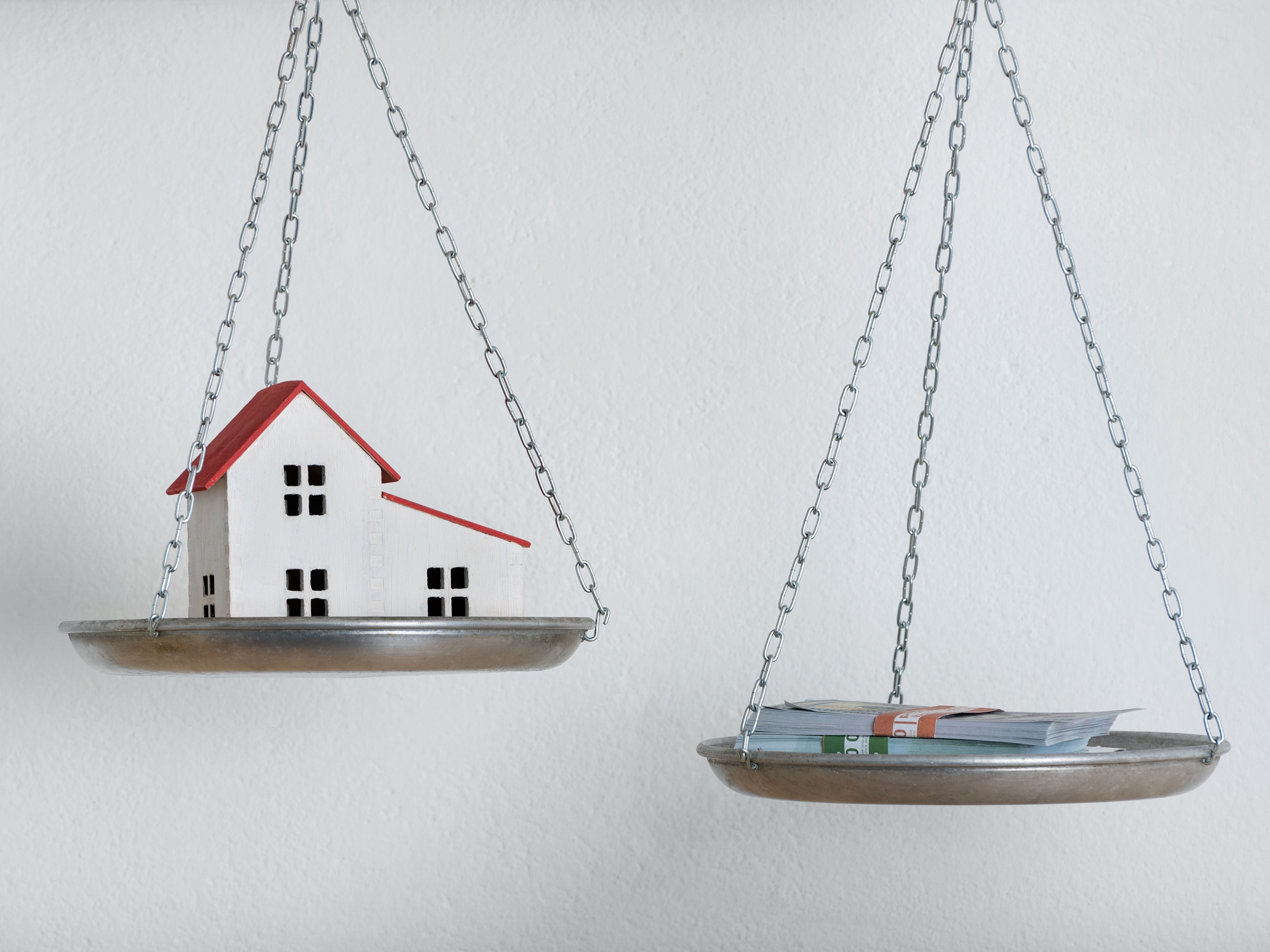 House and money on balancing scales