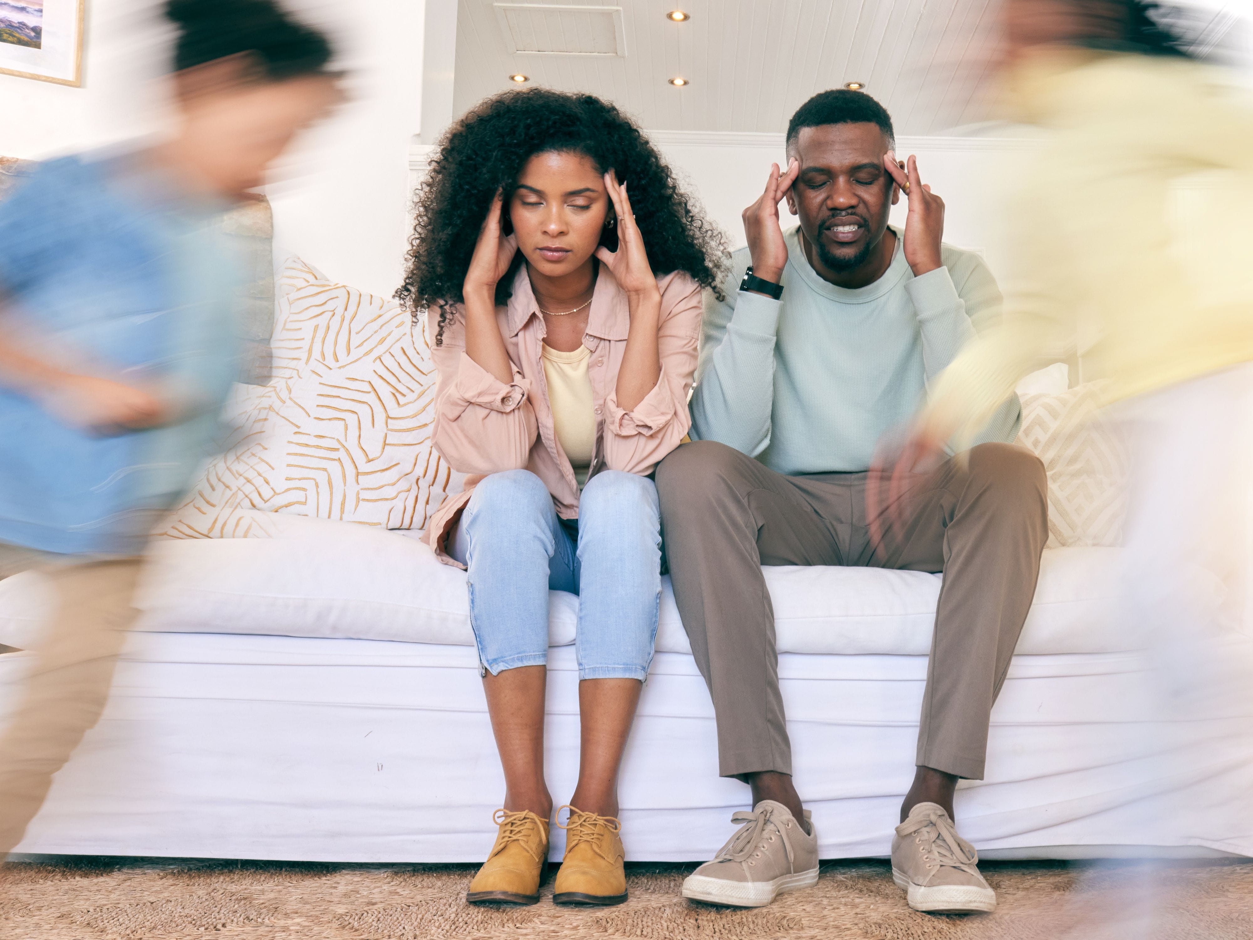 Stressed parents sitting as kids run around them