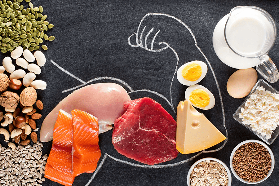 Assortment of protein-rich foods on a chalkboard with muscles