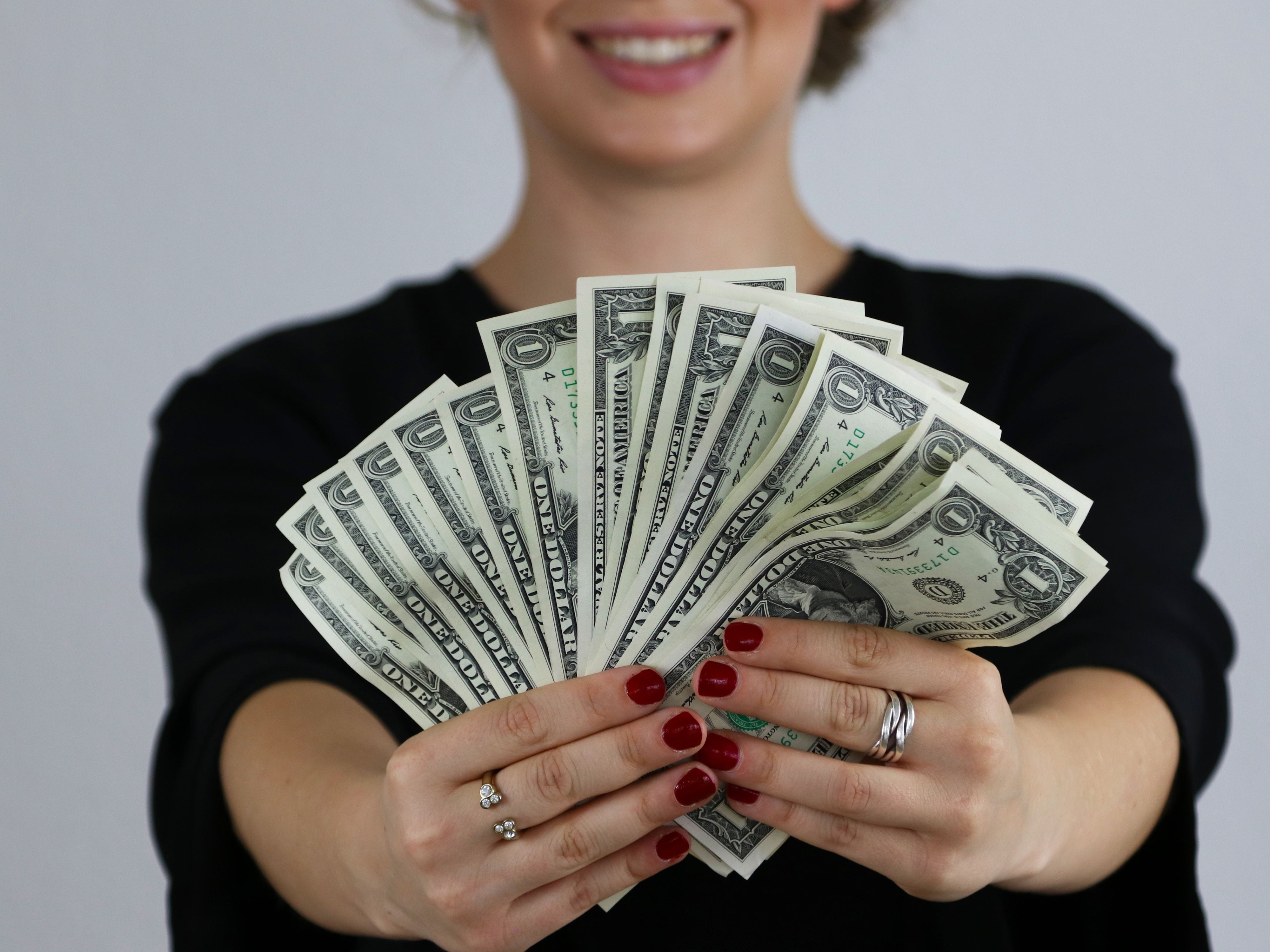 Smiling woman holding fan of cash